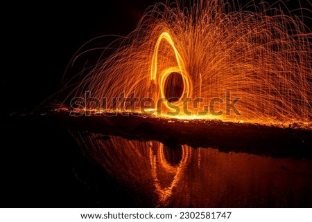 Long exposure photographic images with the steel wool technique made by rotating fire in the dark at night