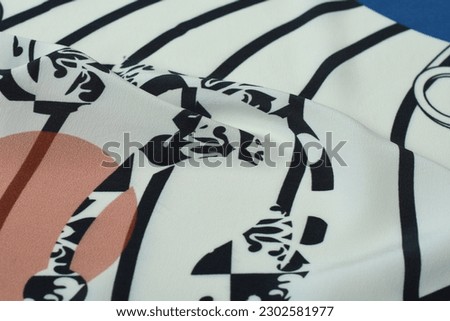 Silk fabric, graphic black and white monograms and dynamic stripes on white background. Geometric pattern on fabric.  Sophisticated design. Delicate fine silk fabric.