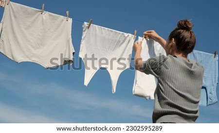 Woman hangs laundry on clothesline Royalty-Free Stock Photo #2302595289