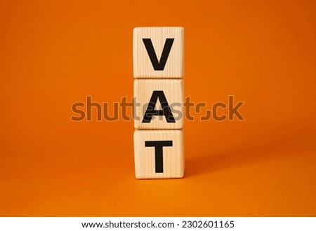 VAT - Value Added Tax symbol. Wooden cubes with word VAT. Beautiful orange background. Business and Value Added Tax concept. Copy space.