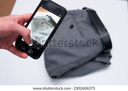 man takes photo of pants. Selling second-hand clothes online