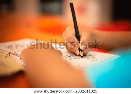Child's hand holding a black pen - coloring.