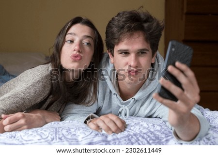 A caucasian male and female college student take selfies together