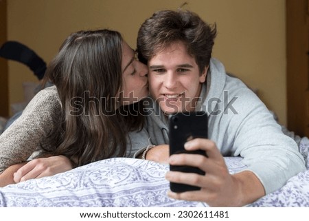 A caucasian male and female college student take selfies together