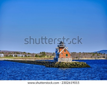 Morning light on the Rockland Breakwater Lighthouse and jetty in Rockland Maine as seen from the Vinalhaven Ferry heading out into open water with the town of Rockland Maine in the background Royalty-Free Stock Photo #2302619015
