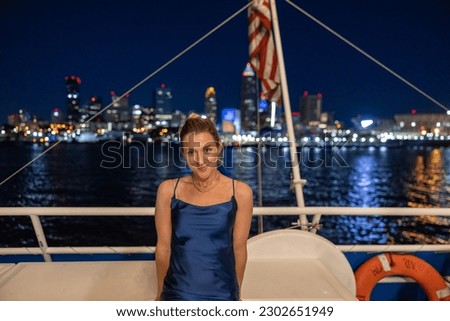 Young woman on a boat with illuminated Cleveland skyline in the background. 