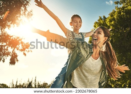 Piggyback, flying and a mother and child in nature for bonding, happiness and love in summer. Laughing, smile and a mom and a girl kid in a park or garden for playing together and quality time Royalty-Free Stock Photo #2302678065