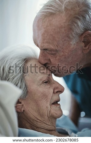 Senior, kiss and couple in hospital for love, visiting sick cancer patient and hope for recovery. Clinic, elderly man and woman kissing on forehead for empathy, kindness and support for healthcare. Royalty-Free Stock Photo #2302678085