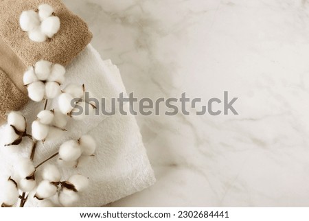 Towels and cotton flowers top view on marble background with copy space.  Neutral colors.  Royalty-Free Stock Photo #2302684441