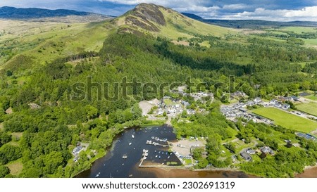 Aerial viewof a conical shaped hill overlooking a small village (Balmaha, Loch Lomond, Scotland) Royalty-Free Stock Photo #2302691319