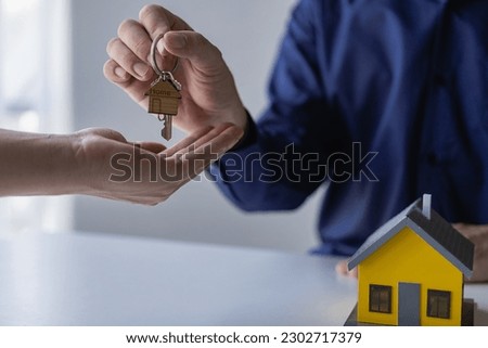 A real estate agent holds a key to a house for his client after signing a concept contract for a business loan, a real estate investment loan, a remote picture.