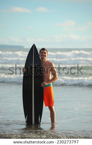 Young surfer with board on the beach