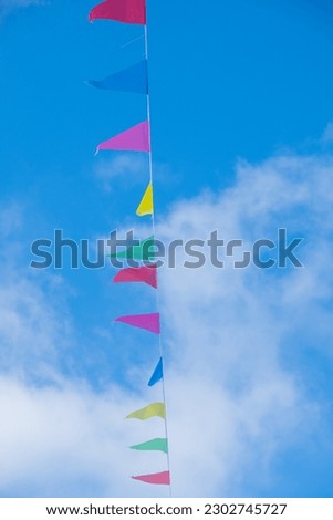 colorful flags with blue sky and clouds in the background.