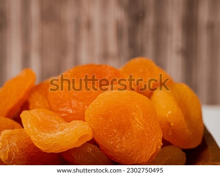 Wooden bowl of dried apricots on a wooden background, selective focus. Dried apricots close up.