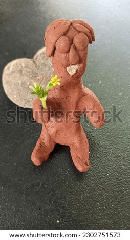 A doll made of earth holding a flower. macro photo. close to object.