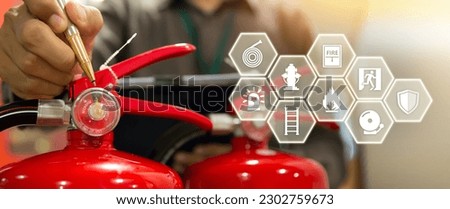 Fire extinguisher has hand engineer checking pressure gauges and prevent icons to prepare fire equipment for protection in emergency case and safety or rescue and alarm system training concept. Royalty-Free Stock Photo #2302759673