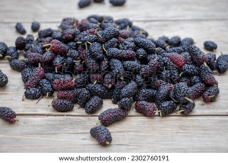black mulberry on a wooden background.close-up. Royalty-Free Stock Photo #2302760191