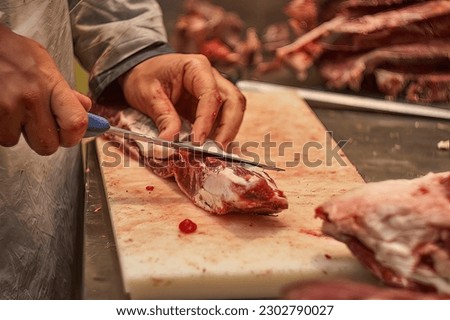 Butcher trying to pull or cut a piece of calf in a butcher shop. Royalty-Free Stock Photo #2302790027