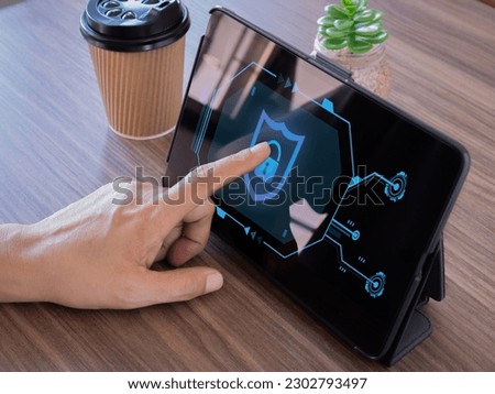 Man pointing finger on padlock icon sign-on digital tablet screen and coffee cup in the office. Security of personal information and data protection. Personal information security concept.

