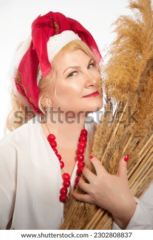 Portrait of heerful funny adult mature woman solokha with sheaf of ears. Female model in national ethnic Slavic style. Stylized Ukrainian, Belarusian or Russian woman in comic photo shoot