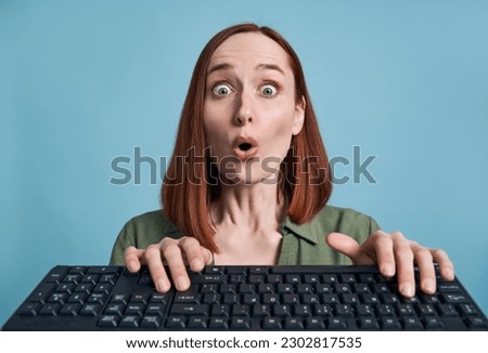 Amazed woman typing on keyboard shopping online with sales, ordering food isolated on blue background. Shocked female playing video game. Innovation concept                            