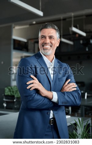 Happy confident middle aged business man, mature professional ceo corporate leader wearing blue suit standing in modern office with arms crossed looking away laughing, authentic vertical portrait. Royalty-Free Stock Photo #2302831083