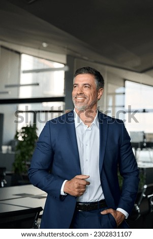 Happy proud mid aged mature professional business man ceo executive wearing suit standing in office looking away thinking of success, enjoying leadership and corporate growth, vertical shot. Royalty-Free Stock Photo #2302831107