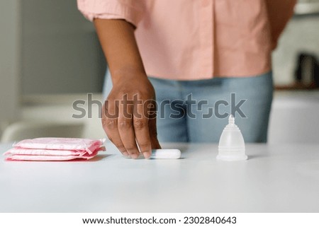 Empowered by period product choices. Black woman choosing between cotton tampons, menstrual cup and pad. Women critical days and hygiene protection Royalty-Free Stock Photo #2302840643