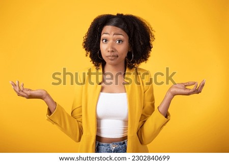 Doubtful black lady shrugging shoulders and spreading arms, unsure hesitant african american woman standing isolated over yellow studio background. Who knows Royalty-Free Stock Photo #2302840699
