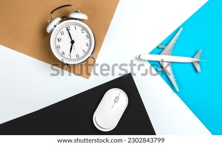 Alarm clock, computer mouse and airplane model on colored paper background.