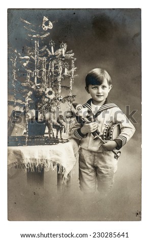 happy boy with christmas tree, gifts and vintage toys. antique sepia picture with original film grain and scratches