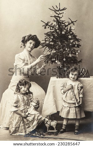 happy mother and children with christmas tree and antique toys. vintage sepia picture with original film grain and scratches