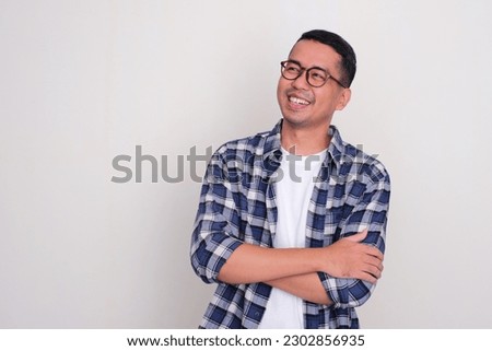 Adult Asian man smiling with arms crossed looking to the right side Royalty-Free Stock Photo #2302856935