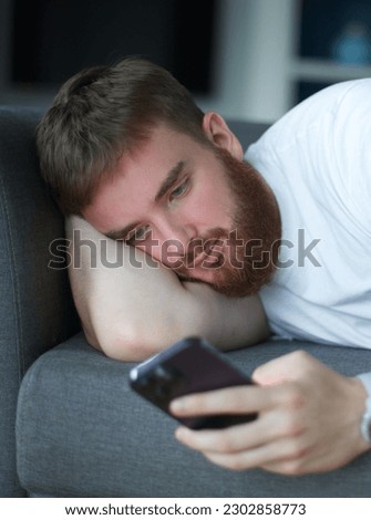 Young adult man relax, boring on sofa using smartphone for online leisure. People good well rest on lazy day at home or apartment concept.