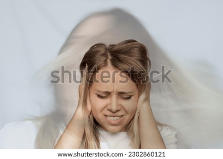 Young blonde woman holds her head and covers her ears with her hands. The girl doesn't want to hear the noise. Voices in the head. Headache. Schizophrenia, split personality, depression, obsession Royalty-Free Stock Photo #2302860121
