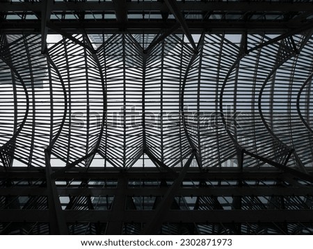 Symmetrical pattern of metals bars on a bridge, seen from underneath with skyscapers and sky above in Toronto, Canada.