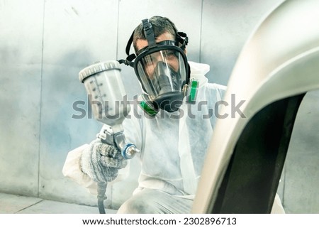 Automotive paint services : Male painters who are skilled in using automotive paint sprayers wearing masks to prevent spray paint dispersion work in a closed spray booth for health and quality work. Royalty-Free Stock Photo #2302896713