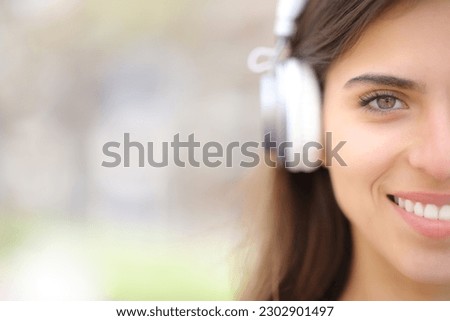 Front view portrait of a happy woman with headphone looks at you outdoors