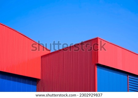 Red and blue Corrugated metal Warehouse Buildings in modern style against blue sky background Royalty-Free Stock Photo #2302929837