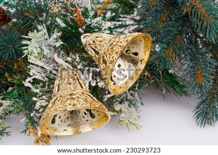 Christmas bells and fir-tree branch on gray background.