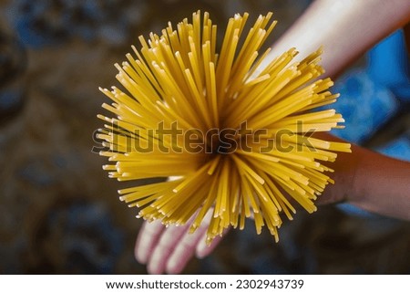 Spaghetti pasta in hand on an empty background. Raw Italian spaghetti on a blue background Royalty-Free Stock Photo #2302943739