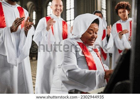Group of people from church choir in white costume singing and playing piano in church Royalty-Free Stock Photo #2302944935