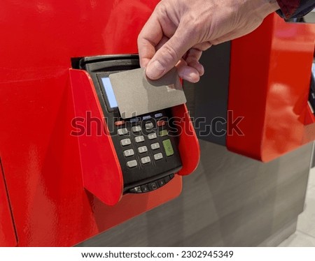 Hand paying with bank card at self-service ordering kiosk, machine, POS terminal. Cashless payment. Royalty-Free Stock Photo #2302945349