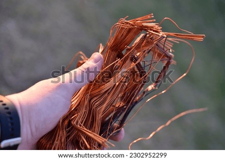 A bundle of copper wire in his hand. Copper scrap. Shiny red copper wire.
