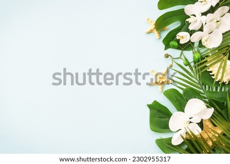 Summer flat lay background tropical leaves on blue.