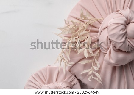 Furoshiki technique. Gifts packed in pink fabric and dried branches on white marble table, flat lay. Space for text