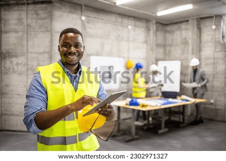 Portrait of African American civil engineer or construction worker holding tablet computer. Royalty-Free Stock Photo #2302971327
