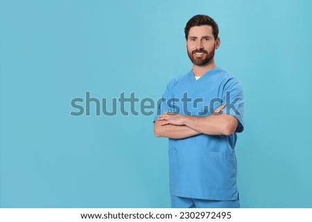 Happy nurse in medical uniform on light blue background, space for text