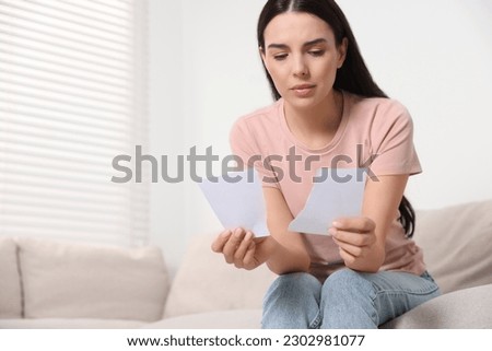 Upset woman holding parts of torn photo at home, space for text. Divorce concept