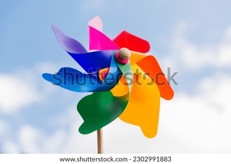ecology, environment and sustainable energy concept - close up of multicolored pinwheel over blue sky Royalty-Free Stock Photo #2302991883